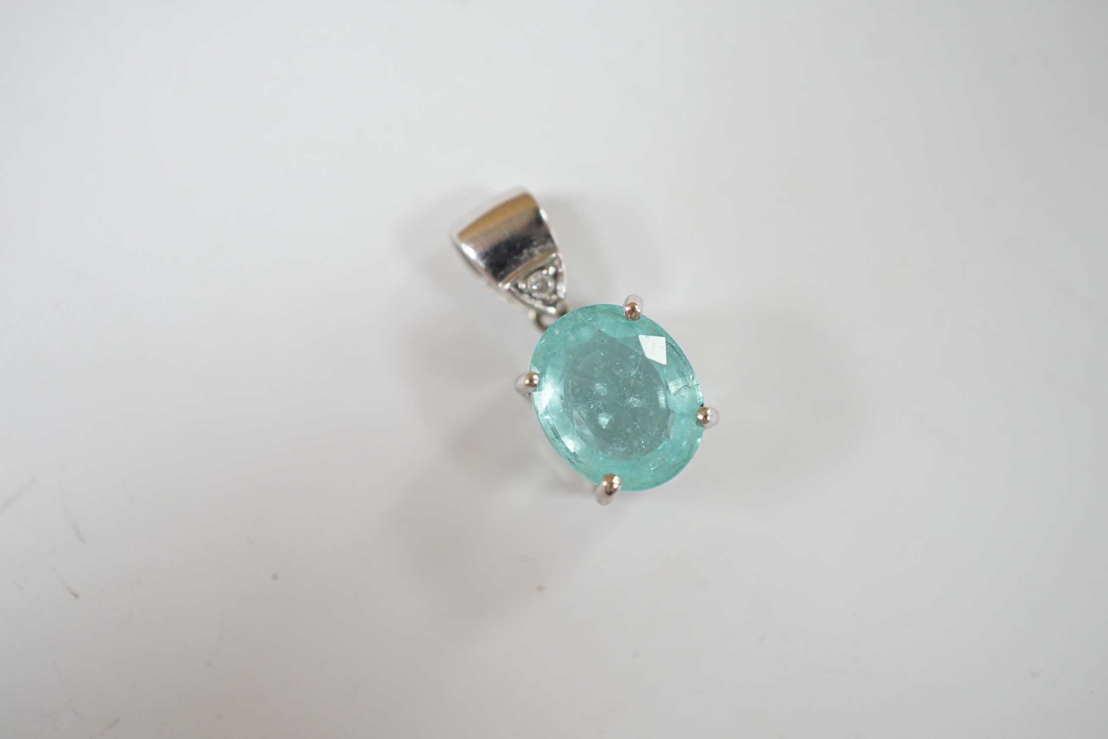 An 18ct white gold and single stone oval cut paraiba tourmaline pendant, with single stone diamond set bale, overall 19mm, gross weight 3.7 grams.